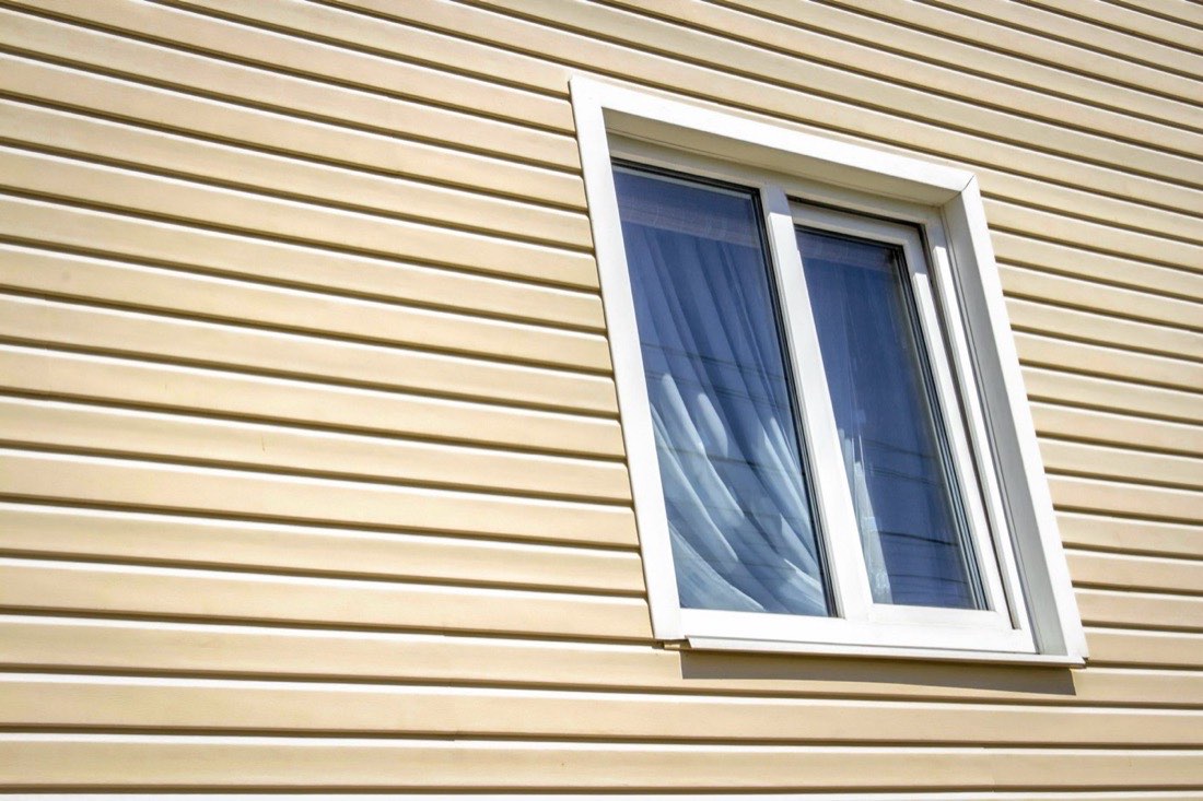 A newly installed white-framed insulated window in the side of a house.